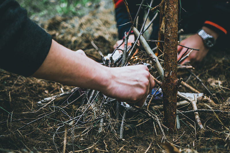 A couple of people setting up a campfire with twigs