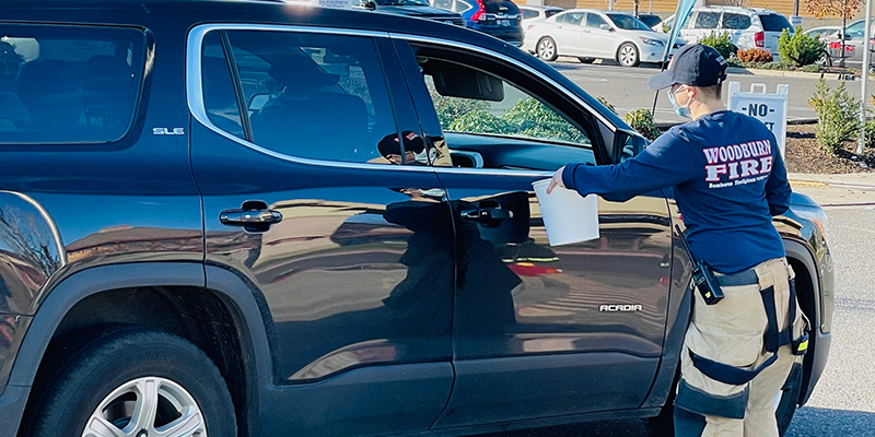 Volunteer handing out bucket to passing car